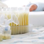 Breast milk frozen in storage bag and baby lying on background